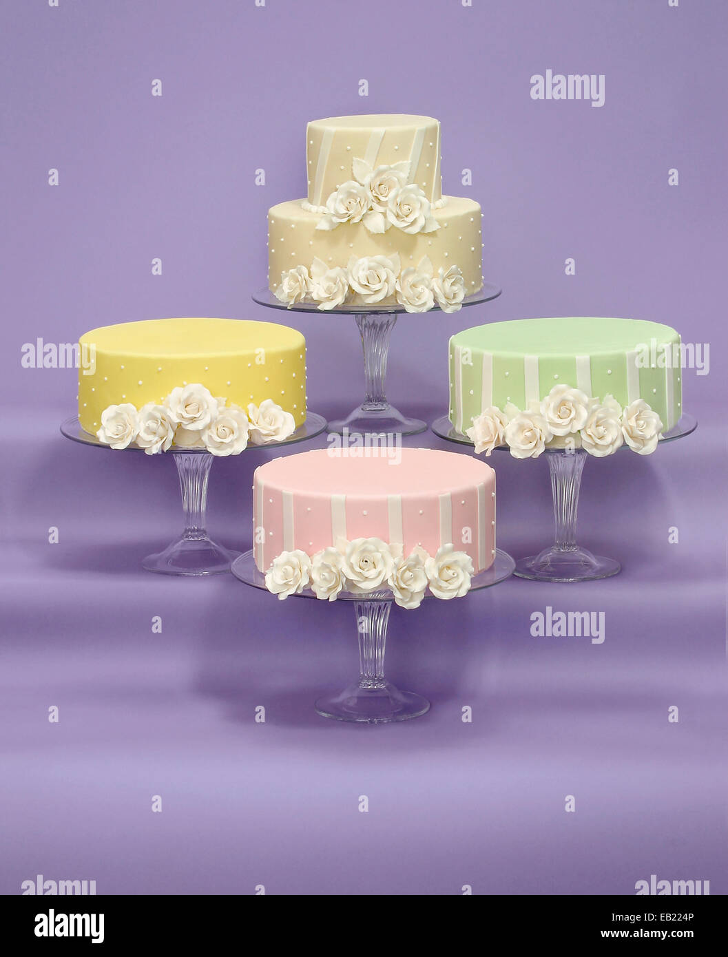 weisse rose Sahnehäubchen auf vier verschiedenen Farben von Hochzeitstorten Stockfoto