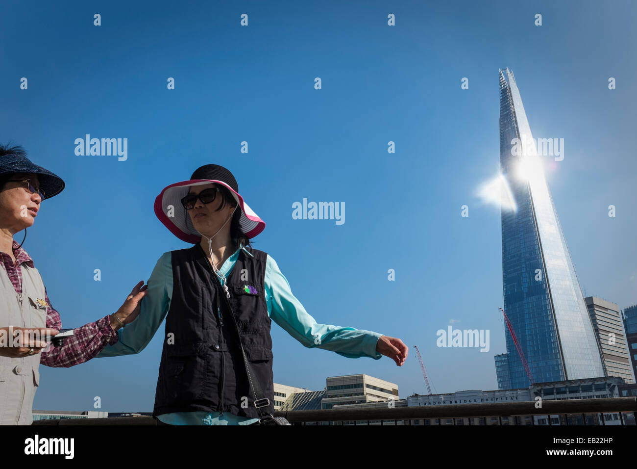 Das Sonnenlicht reflektiert von der Seite der "Splitter" Skyscaper als zwei orientalische Frauen Touristen spazieren durch. Stockfoto