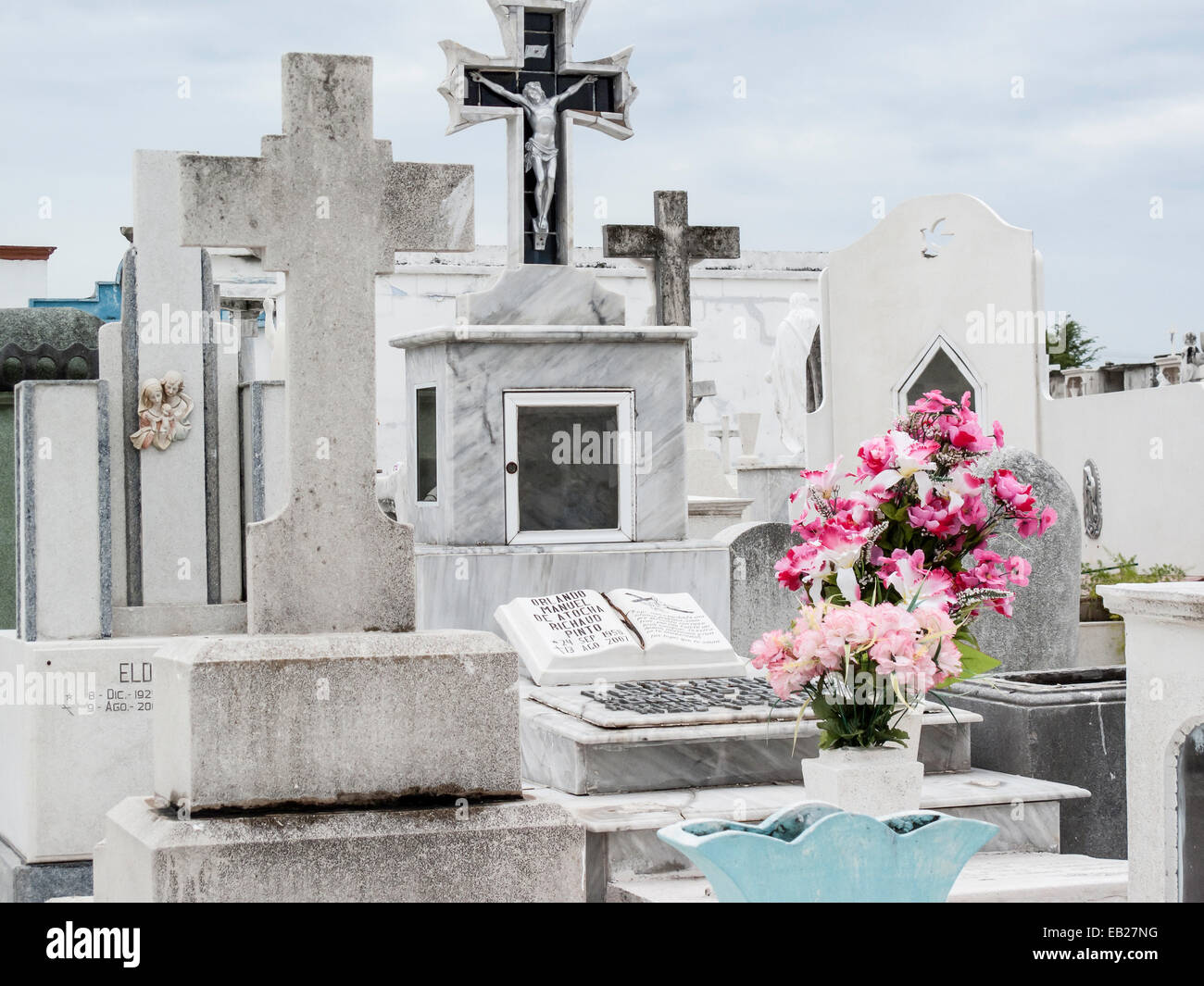 Christliche Gräber aus Marmor und Stein mit Kreuzen und Grabbeigaben von leuchtend rosa Blumen auf dem Friedhof von Pantéon de San Roman, Campeche, Mexiko. Stockfoto