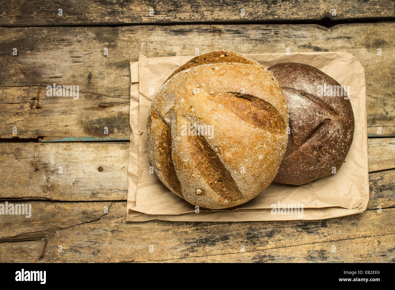 Brote von verschiedenen Arten von Brot auf Holz Hintergrund mit Papiertüte. Ansicht von oben Stockfoto