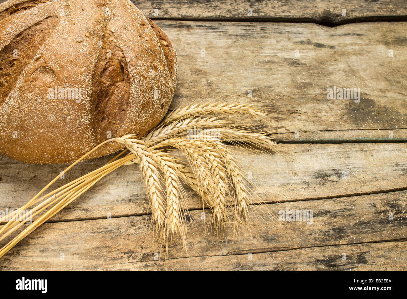 Bäckerei Hintergrund. Frisches Brot am Holztisch mit Weizenähren. Stockfoto