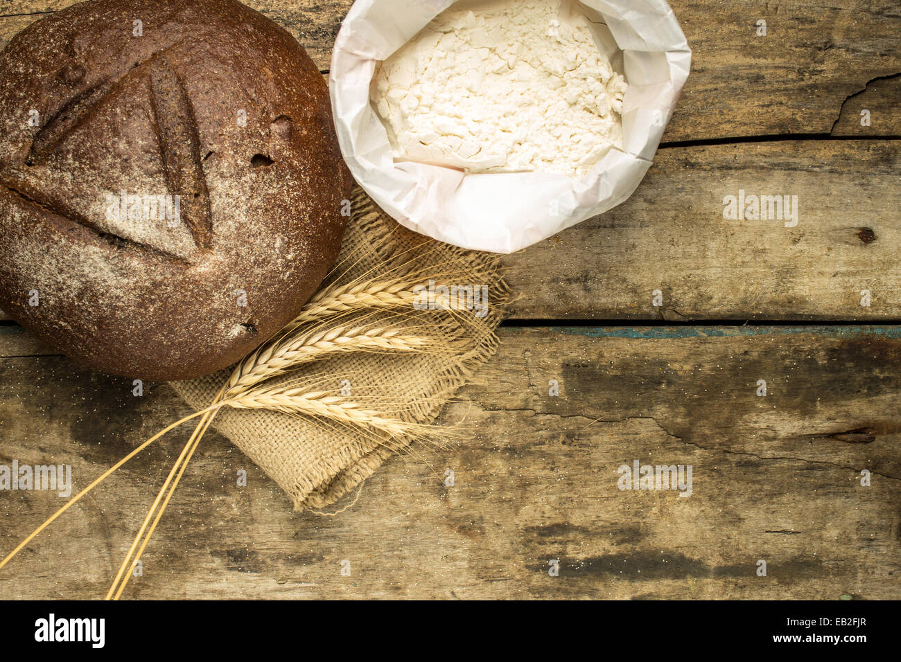 Bäckerei Hintergrund. Roggenbrot mit Ähren und Mehl auf Holztisch Stockfoto