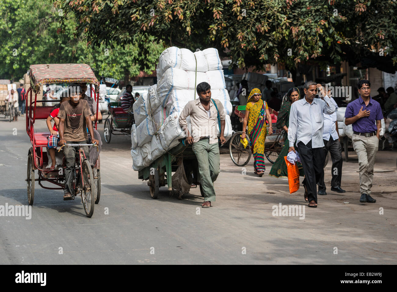 Eine Fahrradrikscha und ein Mann, der Transport von Gütern auf einem Handwagen auf Khari Baoli Road, Old Delhi, New Delhi, Delhi, Indien Stockfoto