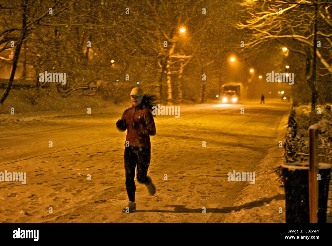 Eine Frau joggt durch den Central Park in einem Schneesturm in der Nacht. Stockfoto