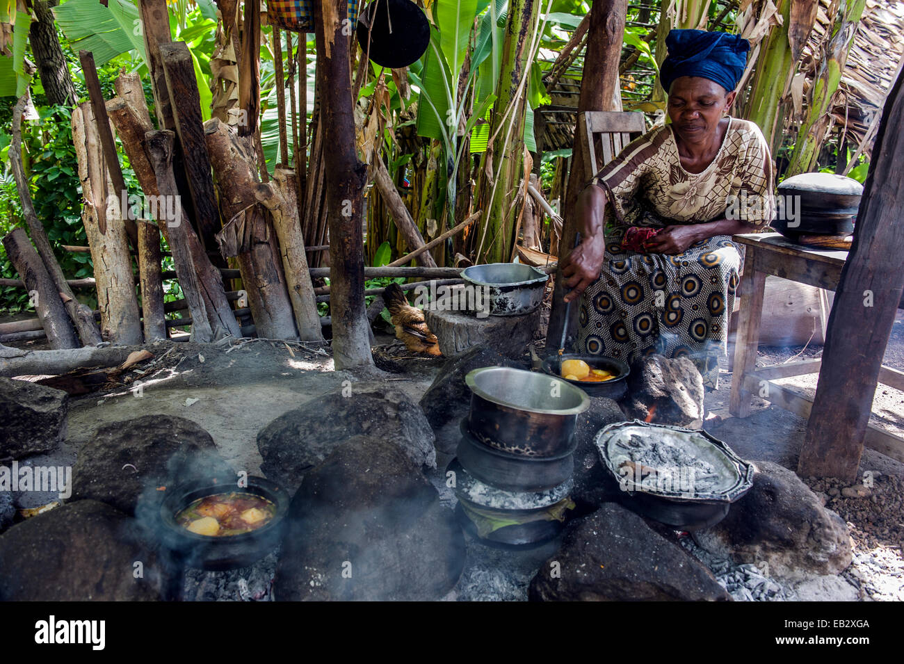 Eine Frau kocht traditionelle afrikanische Gerichte aus Kartoffeln, Fleisch und Gemüse in einer Dorf-Küche. Stockfoto