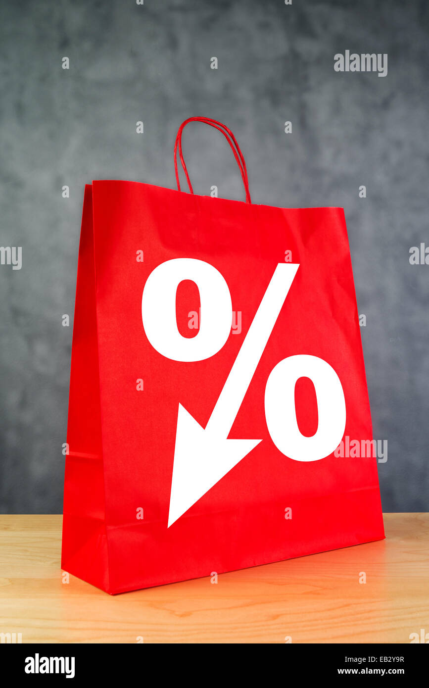 Rabatt Prozentsatz-Symbol auf rote Einkaufstasche auf hölzernen Retail Store-Tabelle. Stockfoto