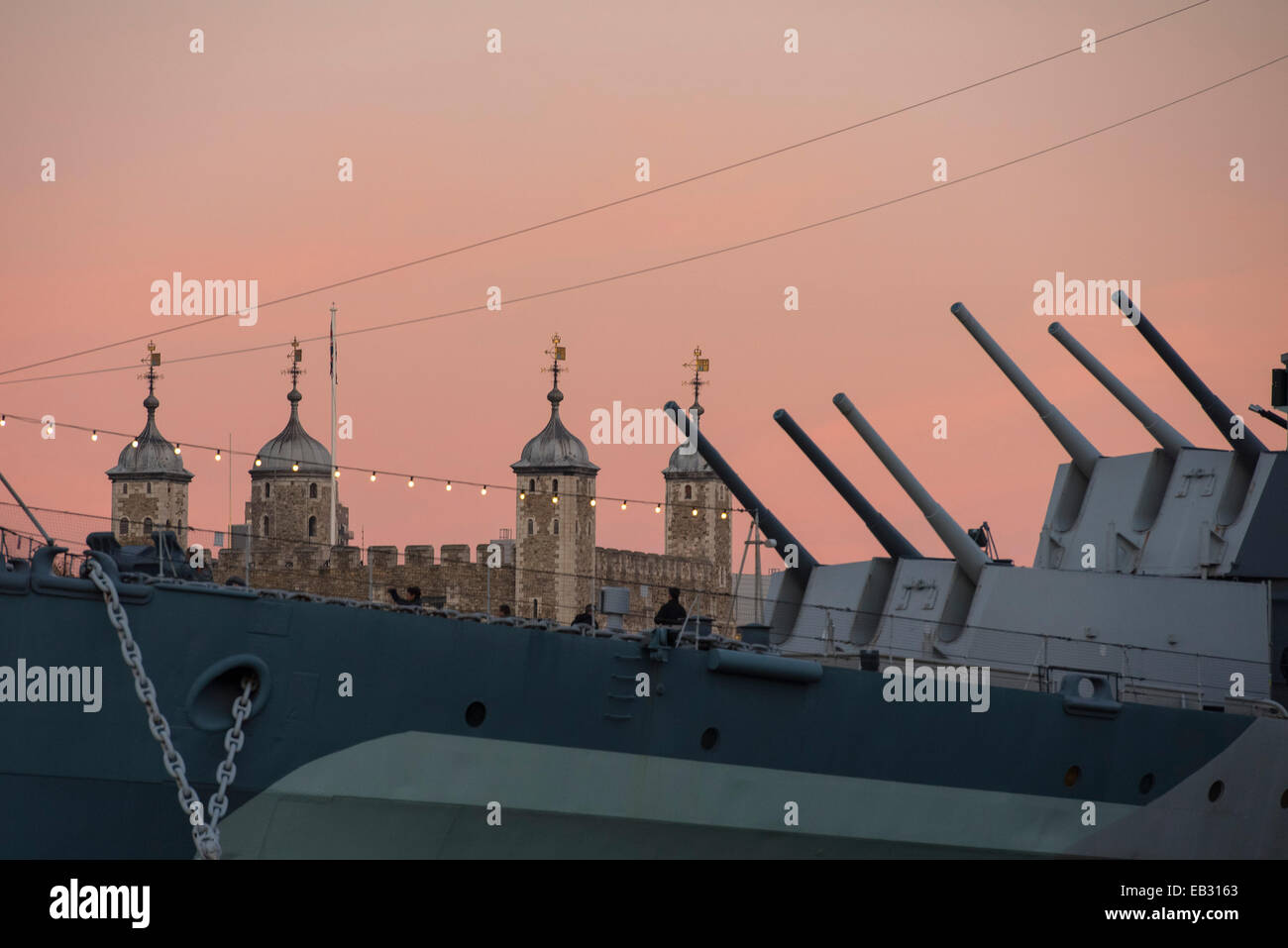 Zentral-London, UK. 24. November 2014. Der letzte Blush Pink erscheint in den Londoner Himmel wie ein hell, aber kalten Wintertag zu einem Ende kommt. Im Bild: HMS Belfast Pistole Turetts Punkt bis zum letzten der Wintersonne am Tag mit dem Tower of London im Hintergrund. Bildnachweis: Lee Thomas/Alamy Live-Nachrichten Stockfoto