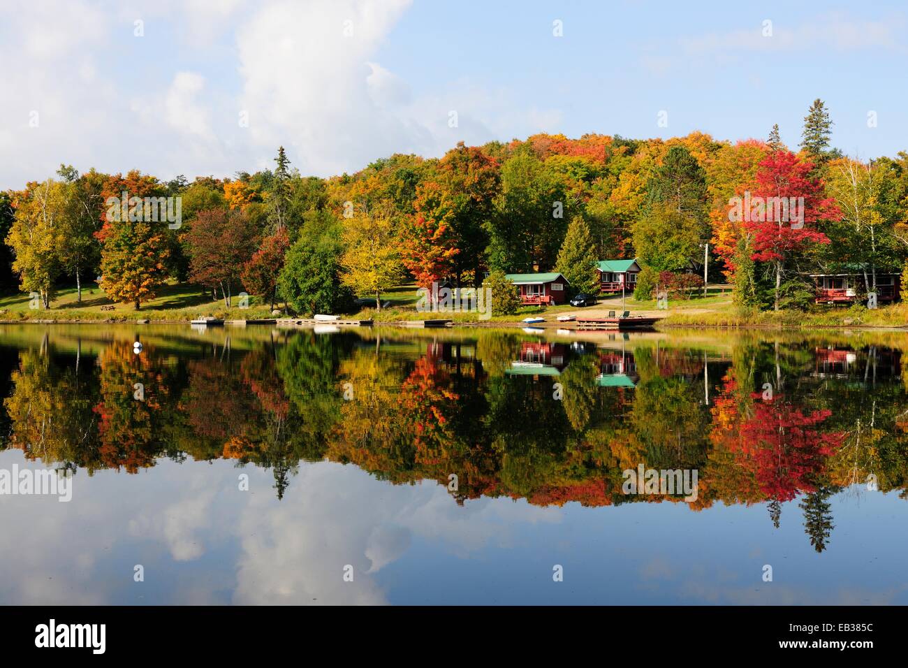Wald in herbstlichen Farben und Häuser spiegeln sich in Galeairy Lake, typische Lake und Waldlandschaft des kanadischen Schildes Stockfoto