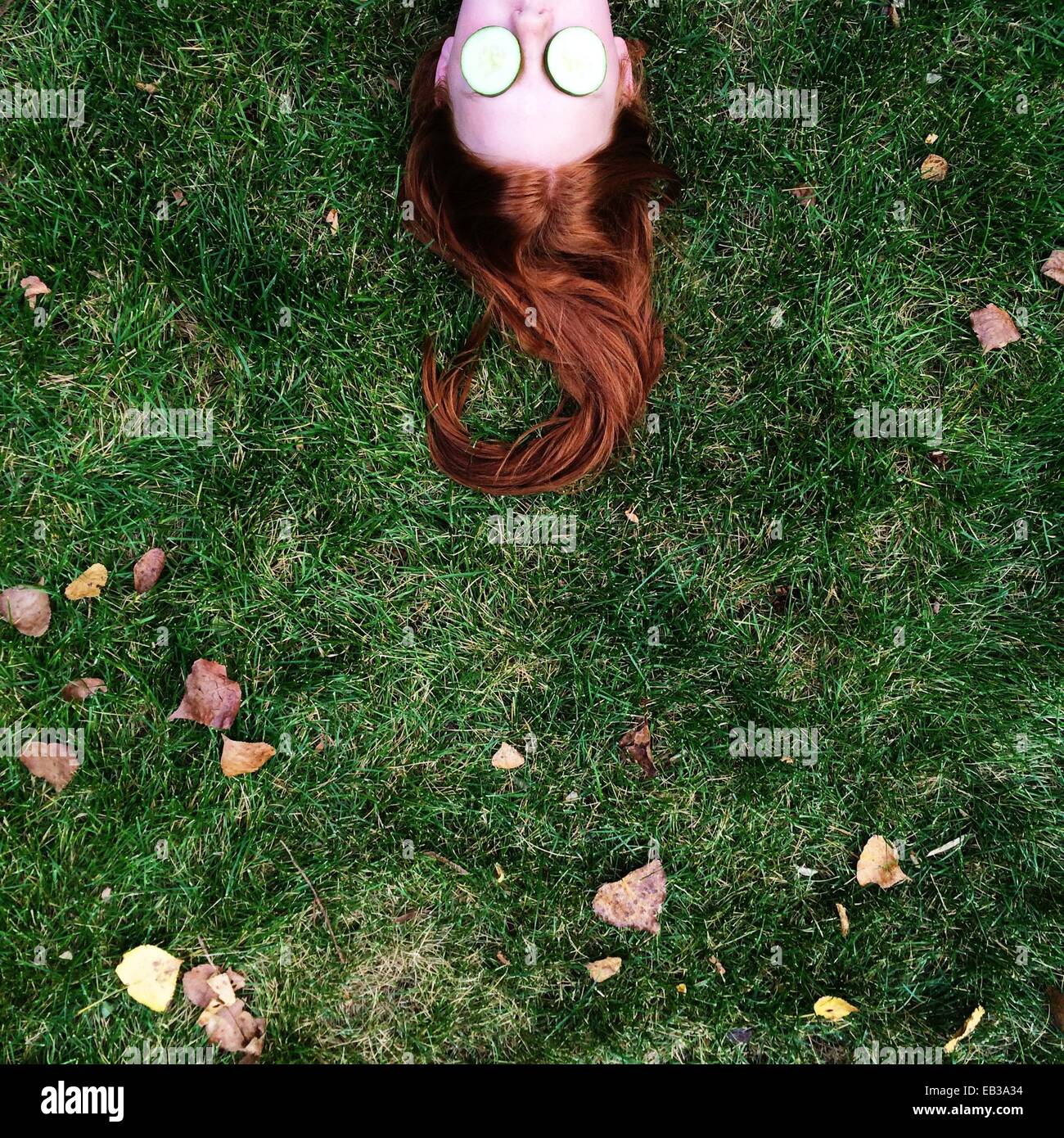 Teenager-Mädchen liegen auf dem Rasen, mit Scheiben Gurken für ihre Augen Stockfoto