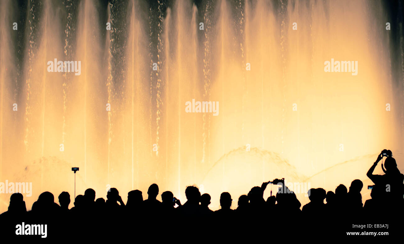 Silhouette von Menschen vor einem beleuchteten Wasserbrunnen Stockfoto