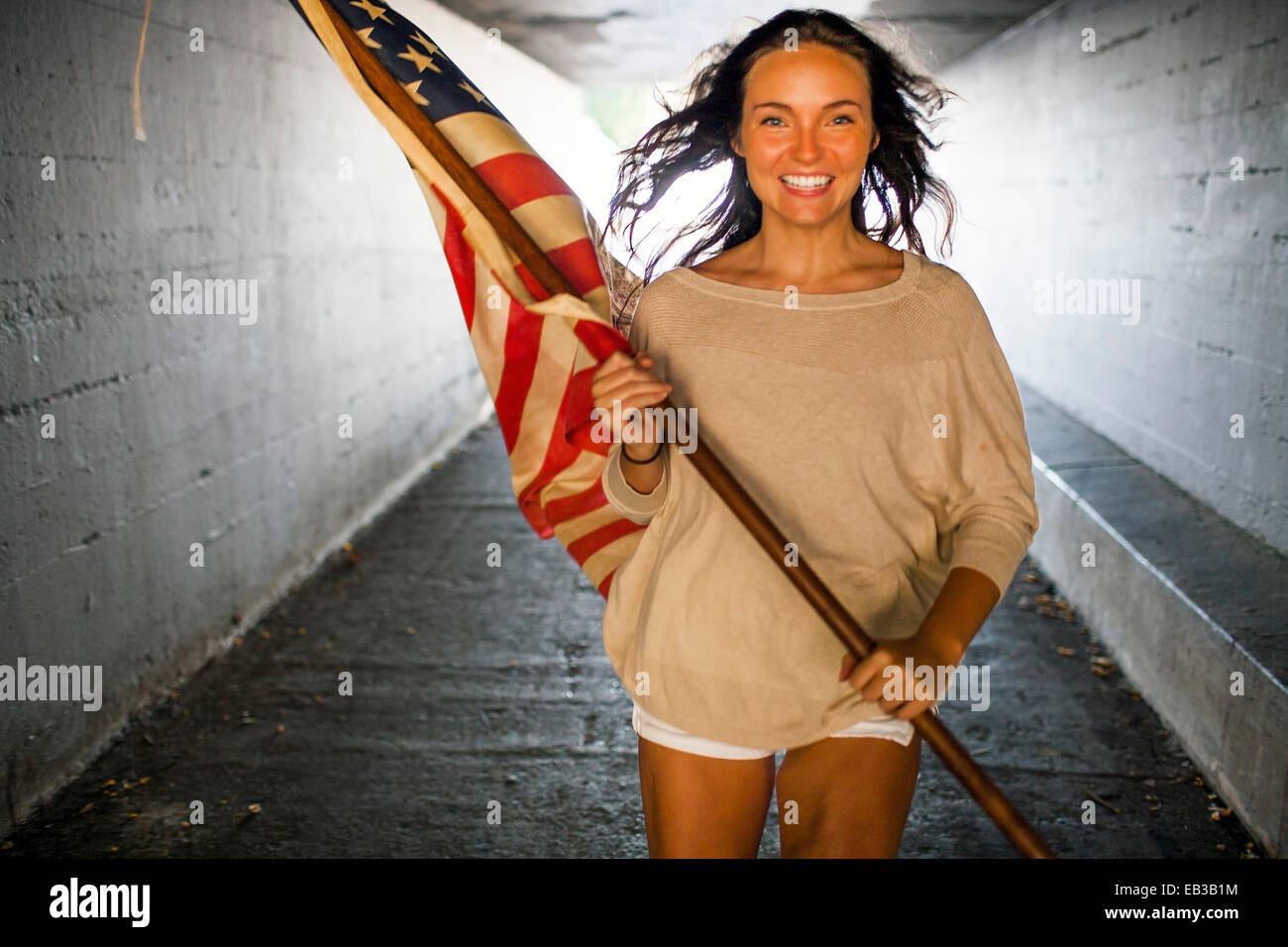 Kaukasische Frau, die die amerikanische Flagge im tunnel Stockfoto