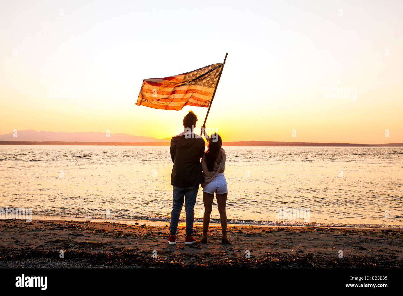 Kaukasische paar mit amerikanischer Flagge am Strand Stockfoto