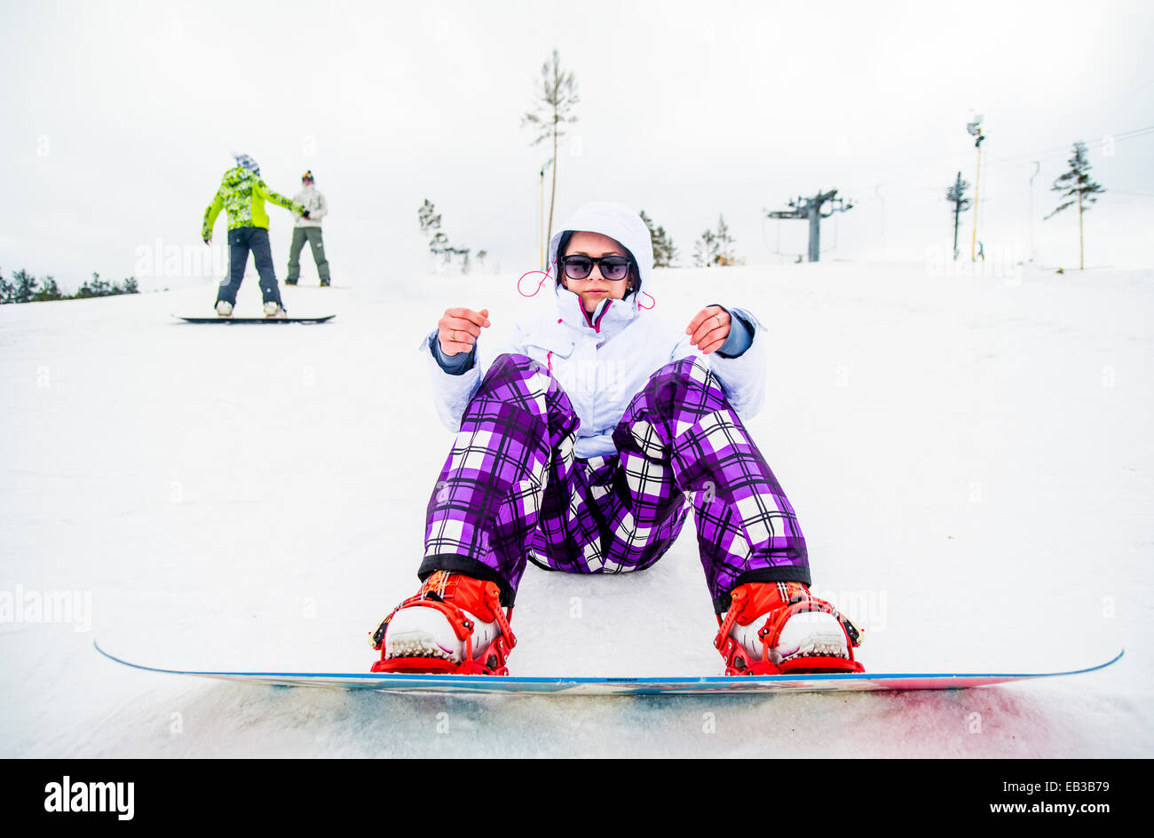 Kaukasische Snowboarder sitzen im Schnee Stockfoto