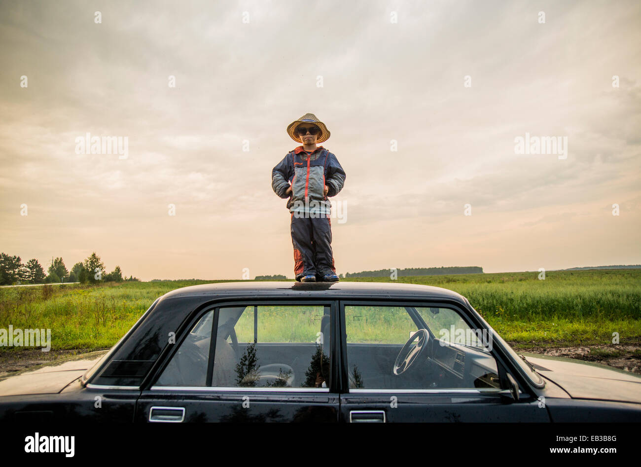 Kaukasische Junge stand auf Autodach im ländlichen Bereich Stockfoto