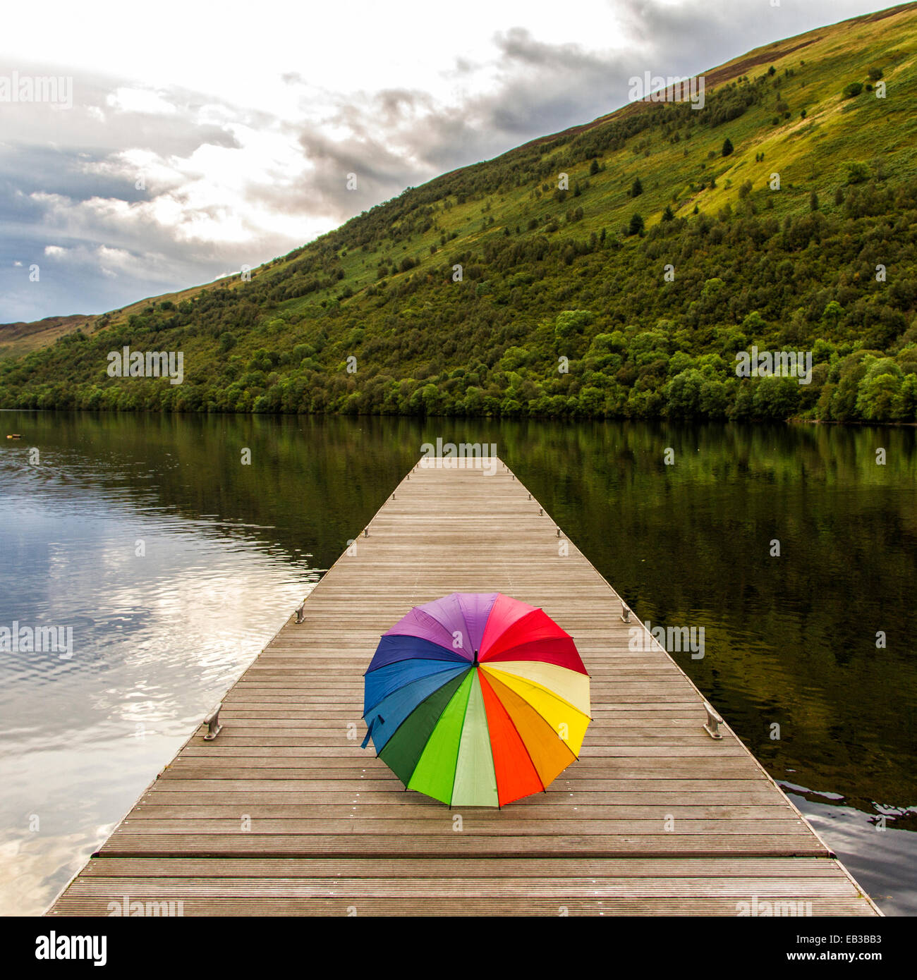 Mehrfarbiger Regenschirm auf Holzsteg, Schottland, Großbritannien Stockfoto