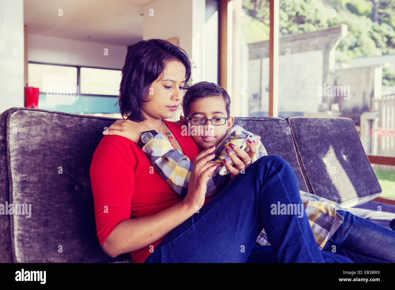 Mutter und Sohn mit Handy im Wohnzimmer Stockfoto