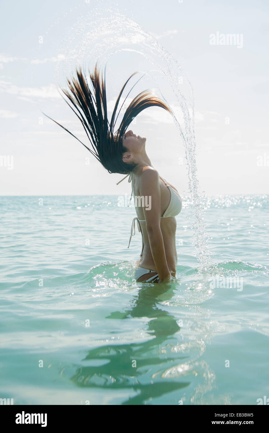 Kaukasische Frau spritzt Haar im Ozean Stockfoto