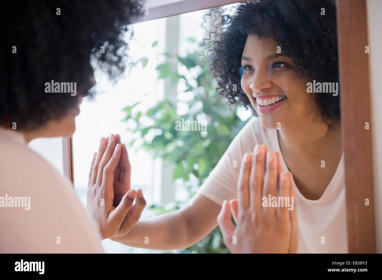 Lächelnde Frau, die sich selbst im Spiegel zu bewundern Stockfoto