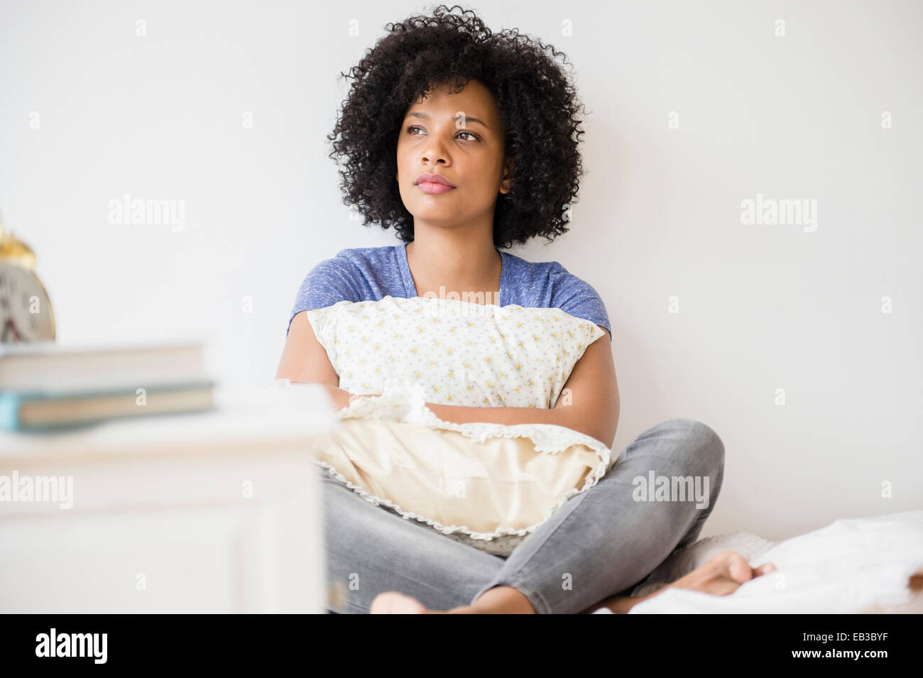 Einsame Frau umarmt Kissen auf Bett Stockfoto