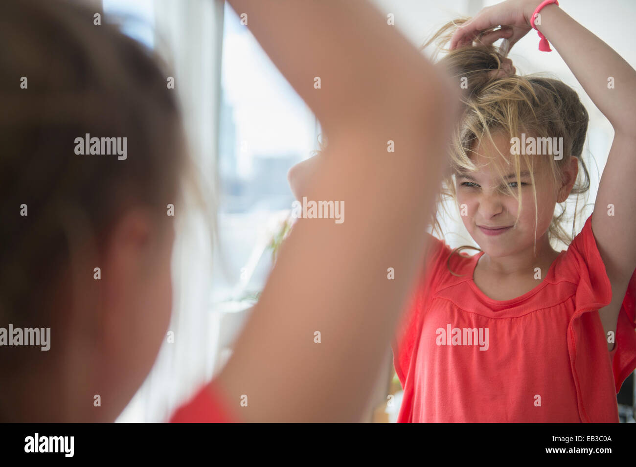 Kaukasische Mädchen spielt mit ihren Haaren am Spiegel Stockfoto