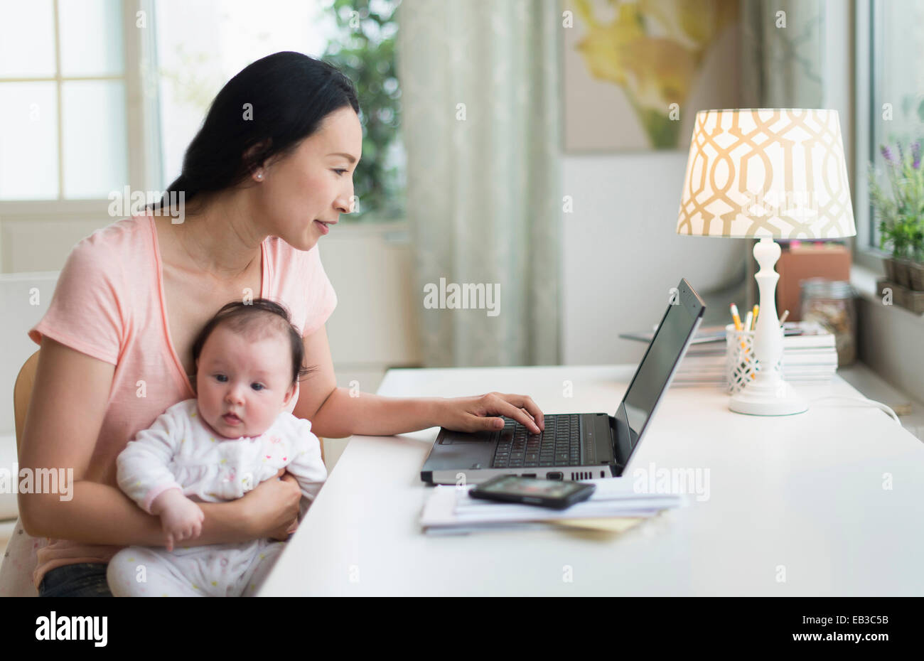 Asiatische Mutter mit Baby von zu Hause aus arbeiten Stockfoto
