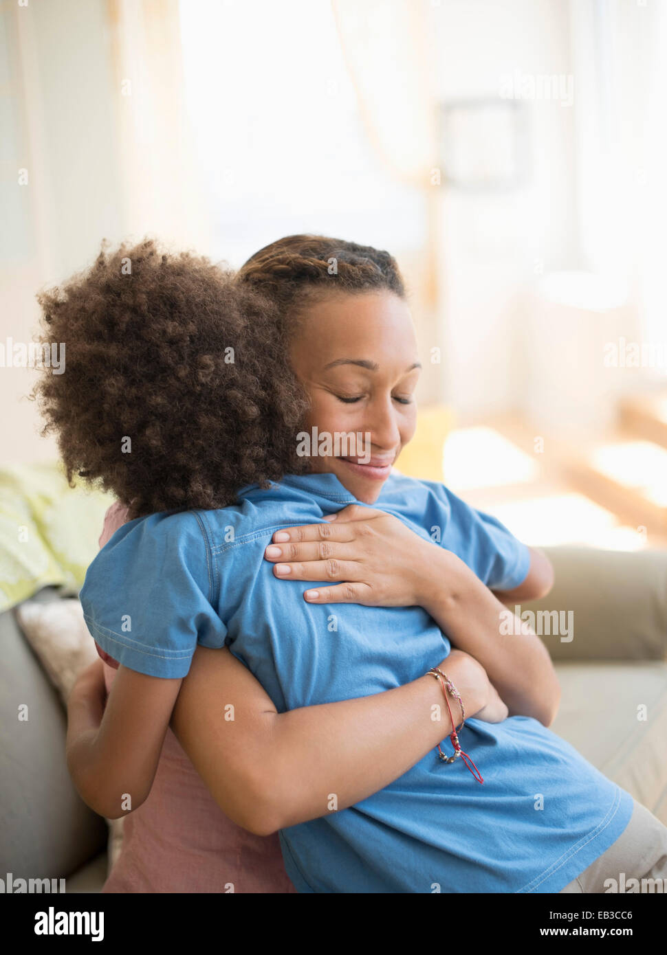Mutter und Sohn umarmt auf Sofa im Wohnzimmer Stockfoto
