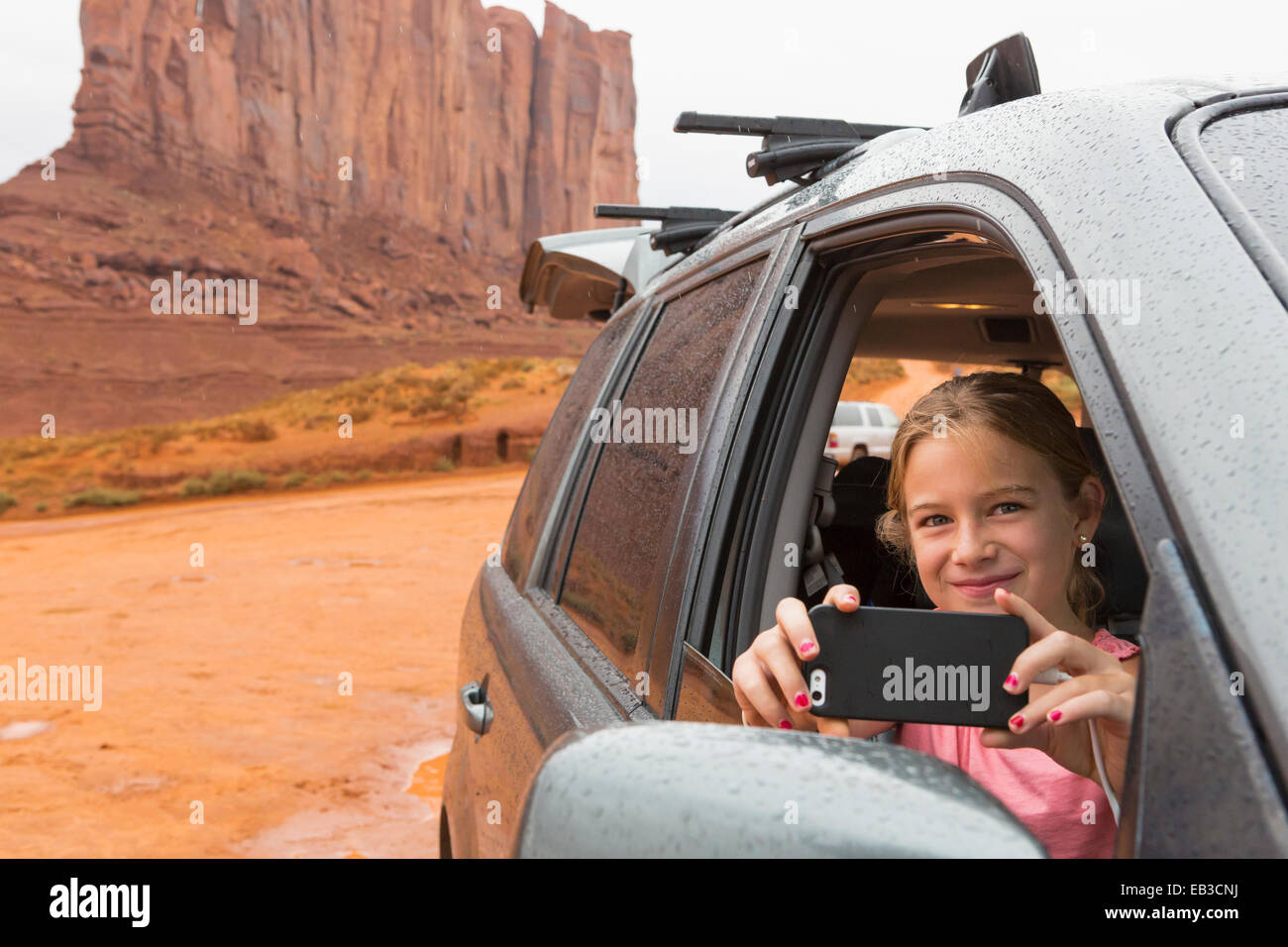 Kaukasische Mädchen Handy fotografieren aus dem Auto, Monument Valley, Utah, Vereinigte Staaten von Amerika Stockfoto