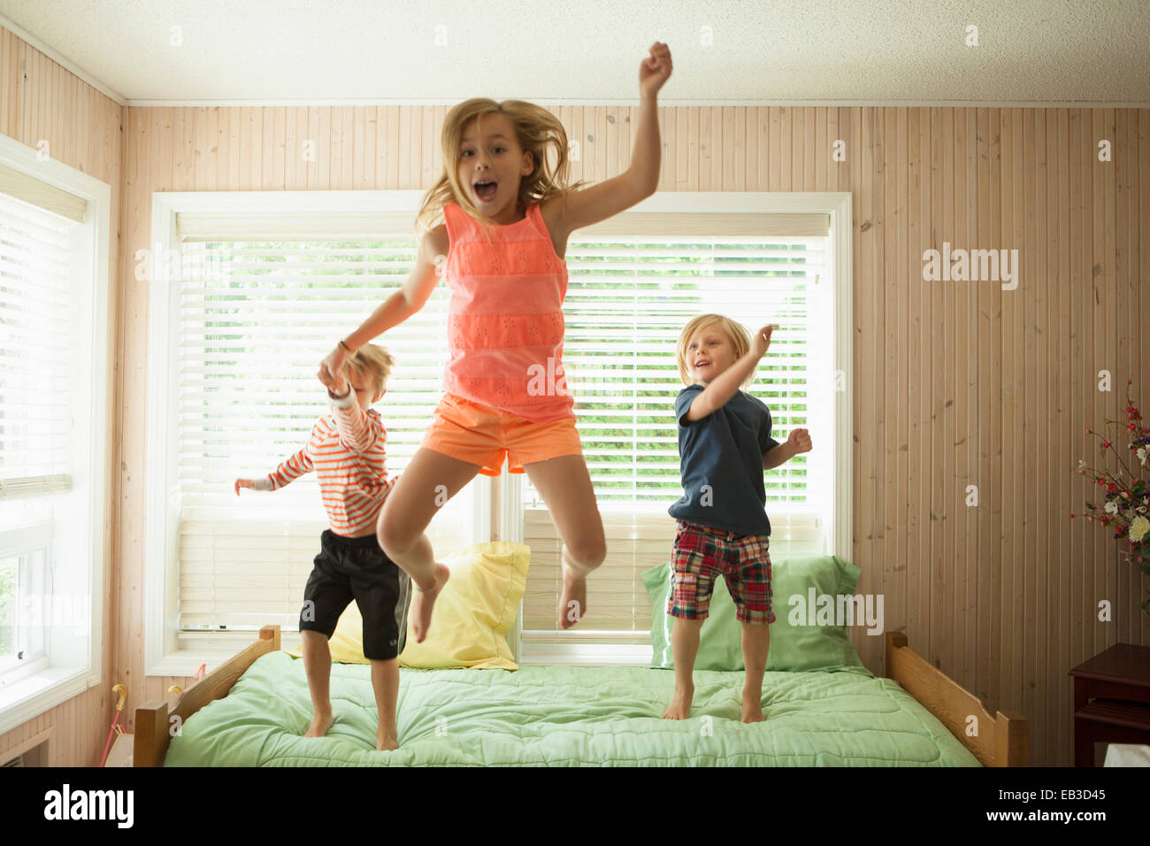 Kaukasische Kinder springen auf Bett Stockfoto