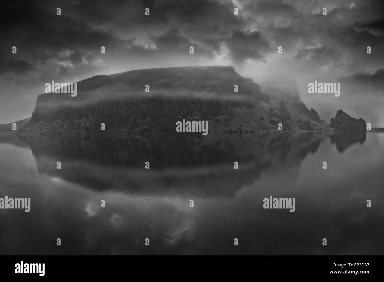 Verschneiten Berg unter bewölktem Himmel spiegelt sich im See Stockfoto