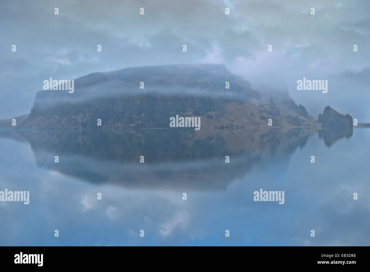 Verschneiten Berg unter bewölktem Himmel spiegelt sich im See Stockfoto
