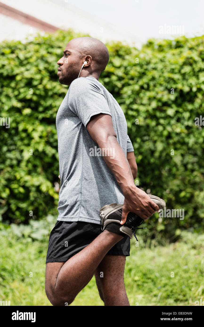Schwarze Läufer mit Ohrhörern Dehnung Bein Stockfoto