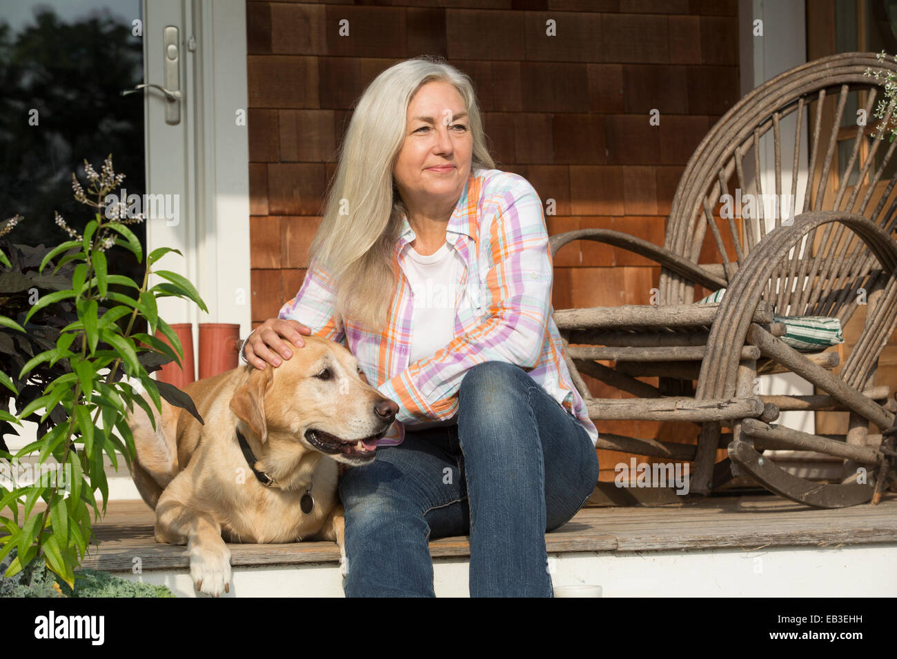 Älteren kaukasischen Frau Petting Hund auf Veranda Stockfoto