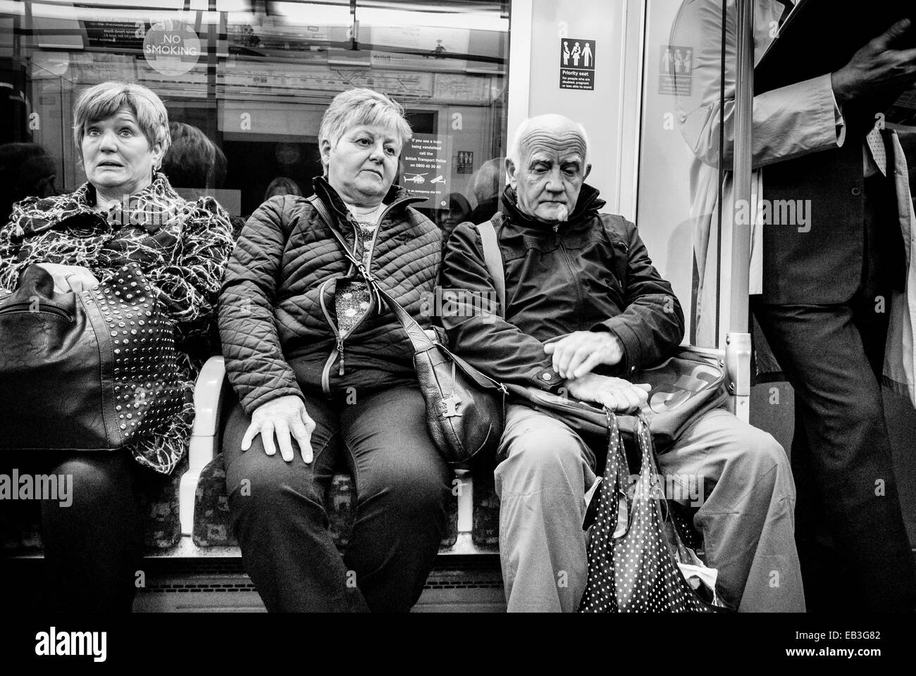 Drei reife kaukasische Erwachsene, die in einer U-Bahn sitzen. Stockfoto