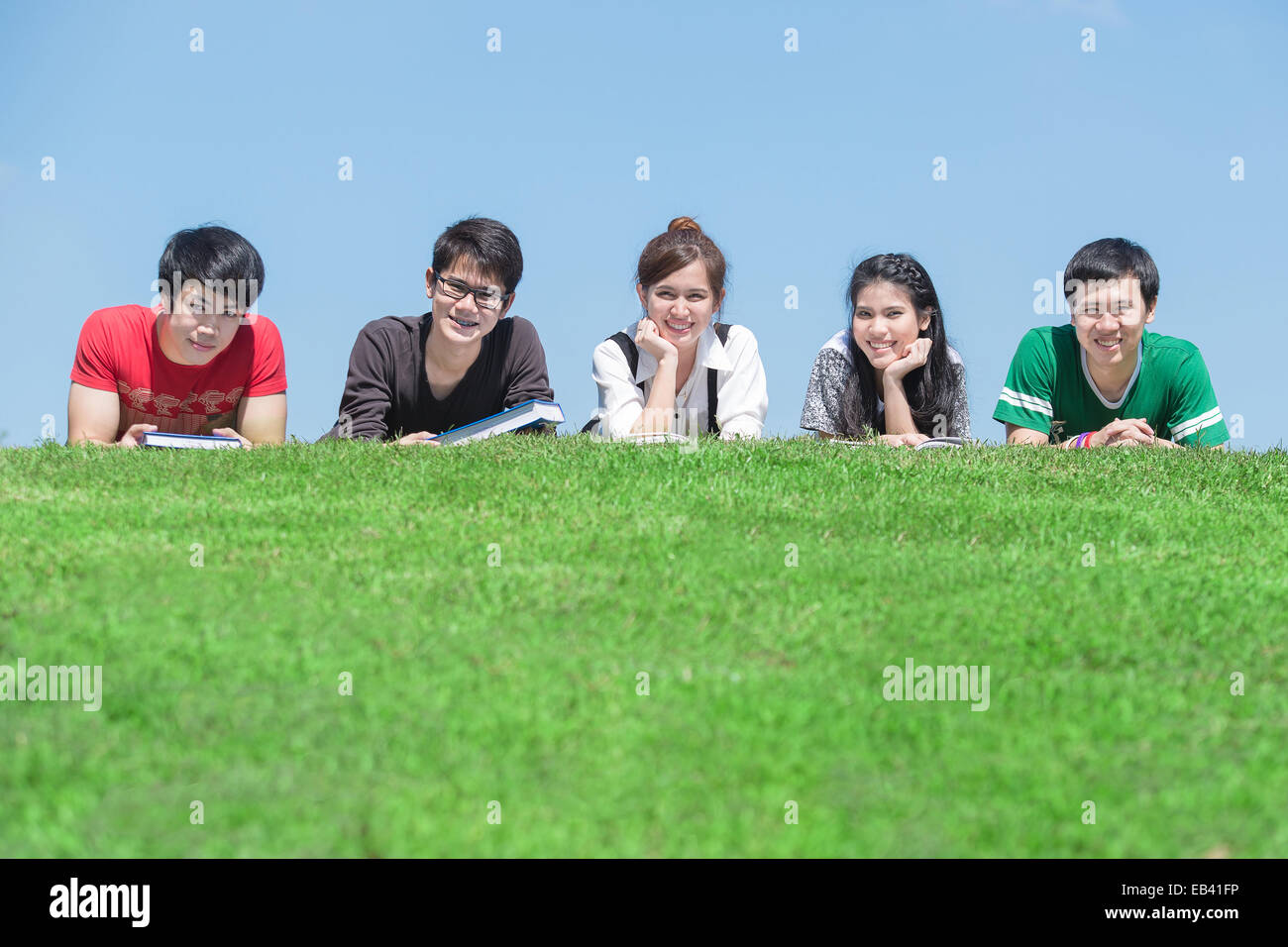 Gruppe von Studenten im Freien auf dem Boden liegend und lächelnd Stockfoto
