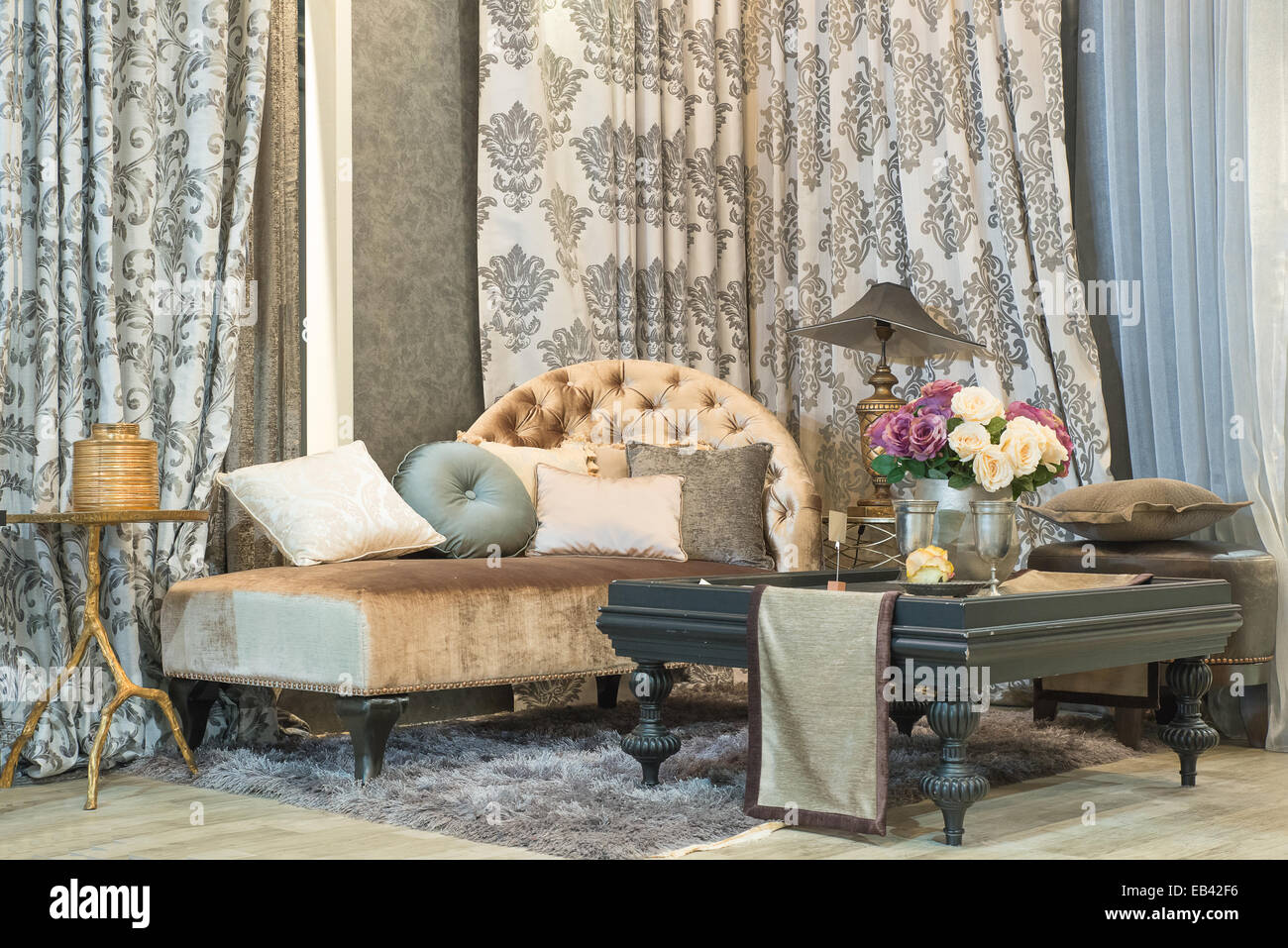 Wohnzimmer mit klassischen aussehendes Sofa, Luxus Gardinen, Lampe und Glas Tisch Stockfoto