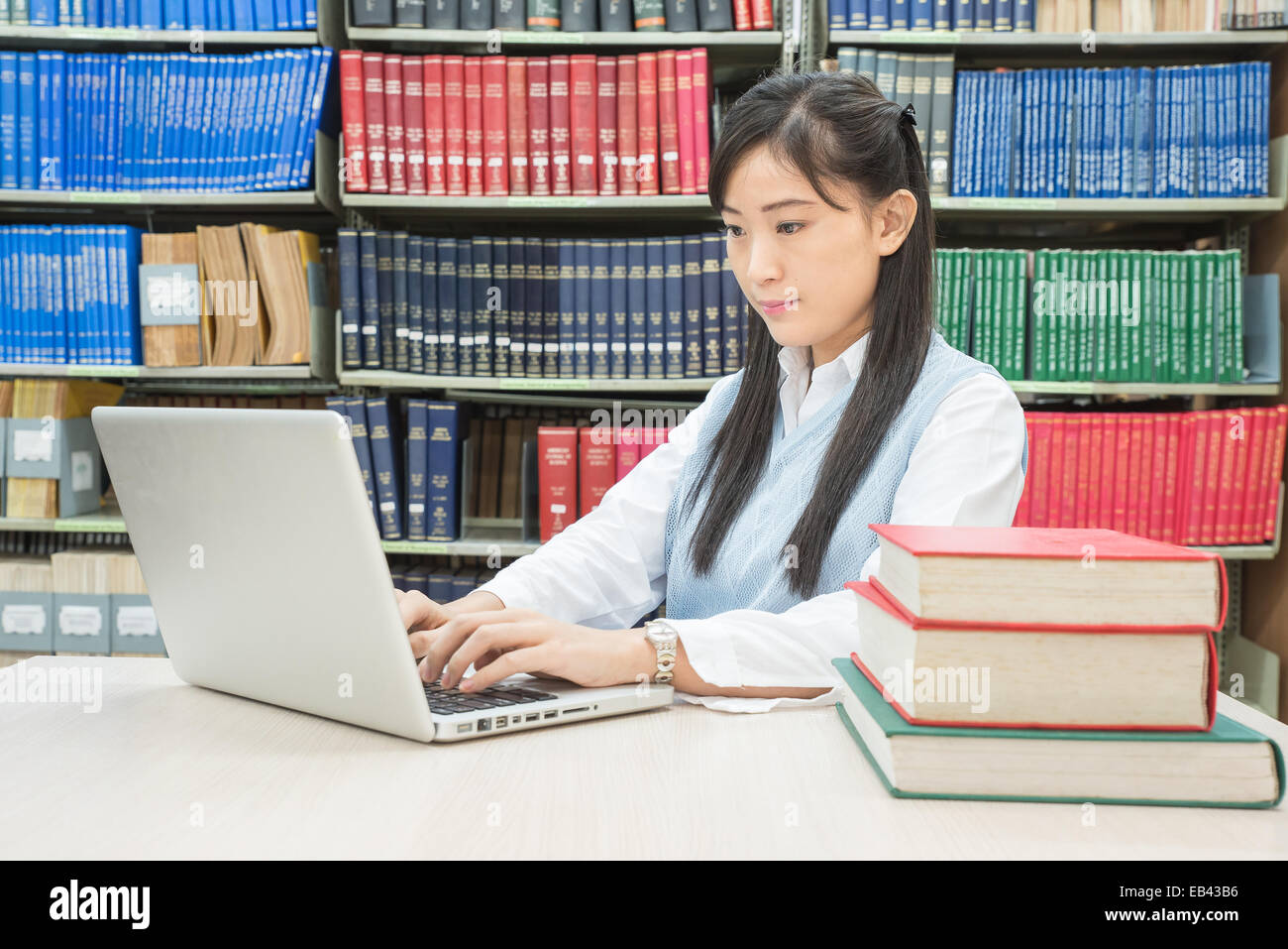 Asiatische Studentin Tippen auf Notebook in Bibliothek Stockfoto