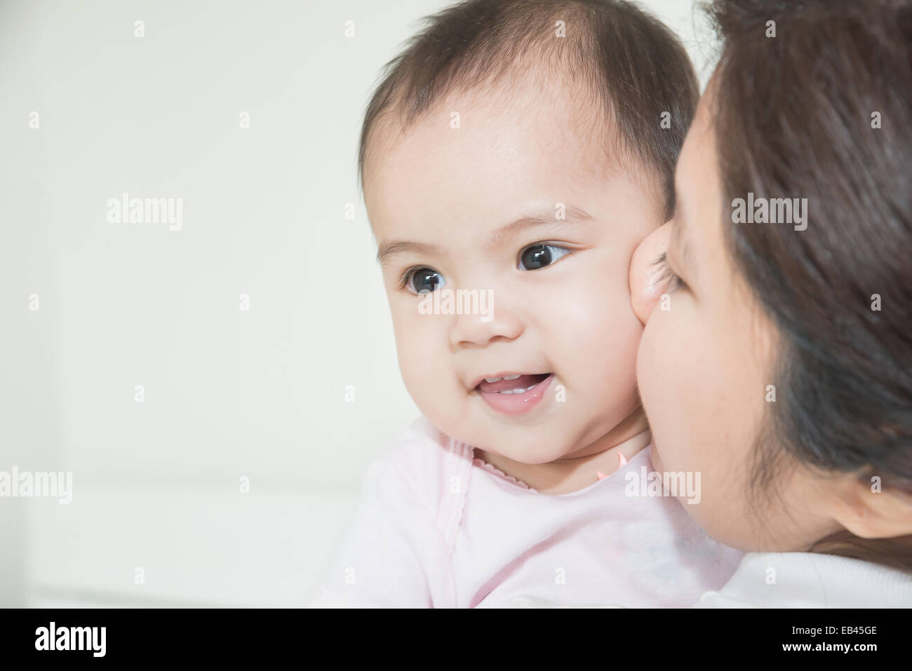 Glückliche Familie fröhlich. Asiatische Mutter und Baby küssen, lachen und umarmen Stockfoto