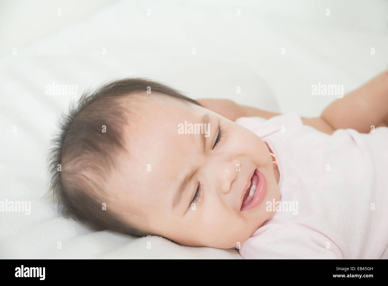 Süße Asiatin Baby weint im Bett Stockfoto