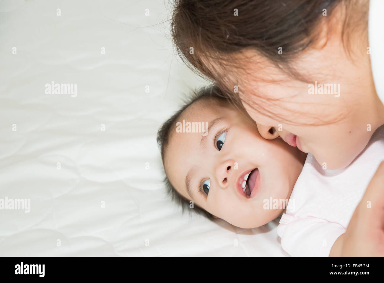 Glückliche Familie fröhlich. Asiatische Mutter und Baby küssen, lachen und umarmen Stockfoto