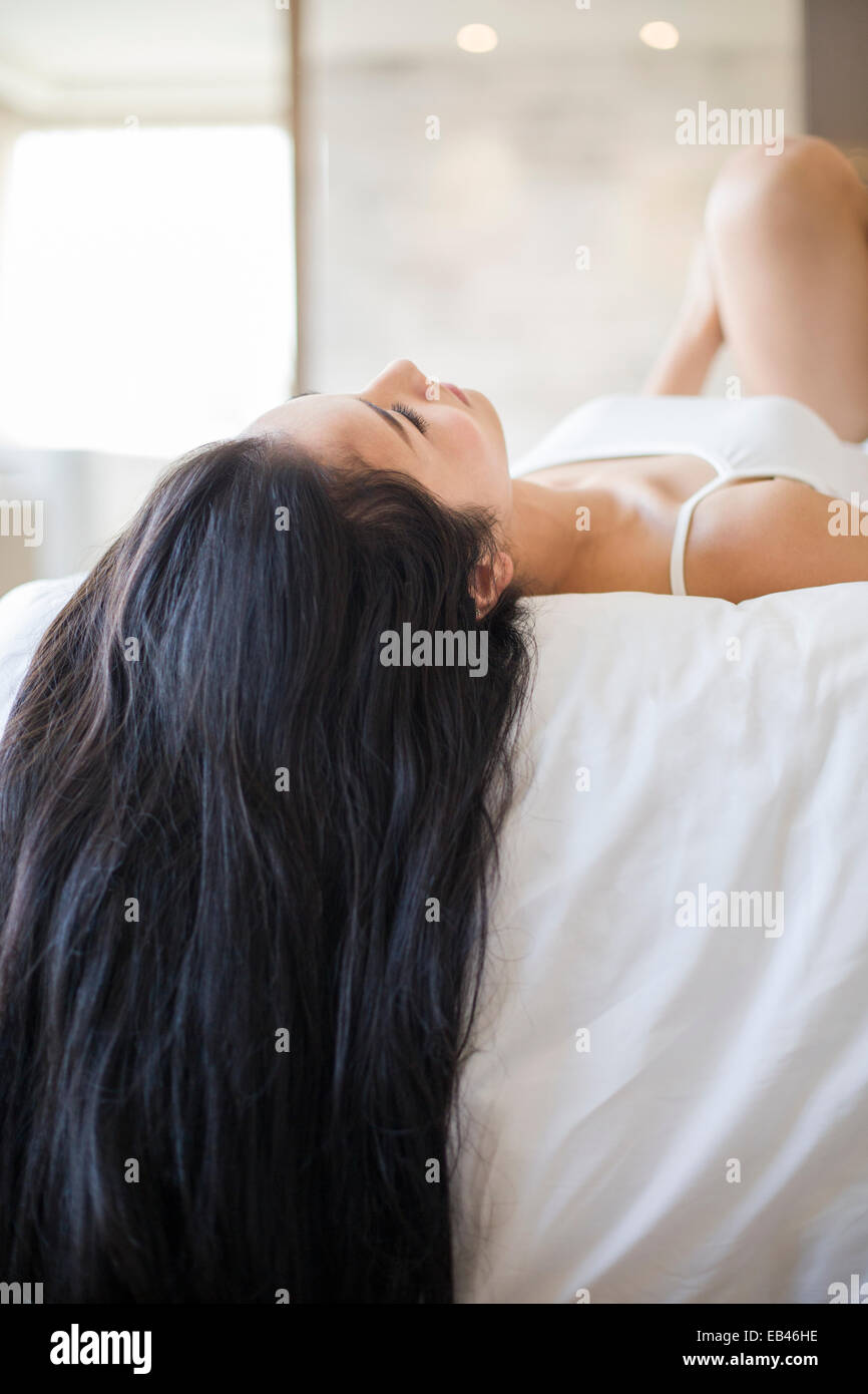 Junge Frau mit langen Haaren auf Bett liegend Stockfoto