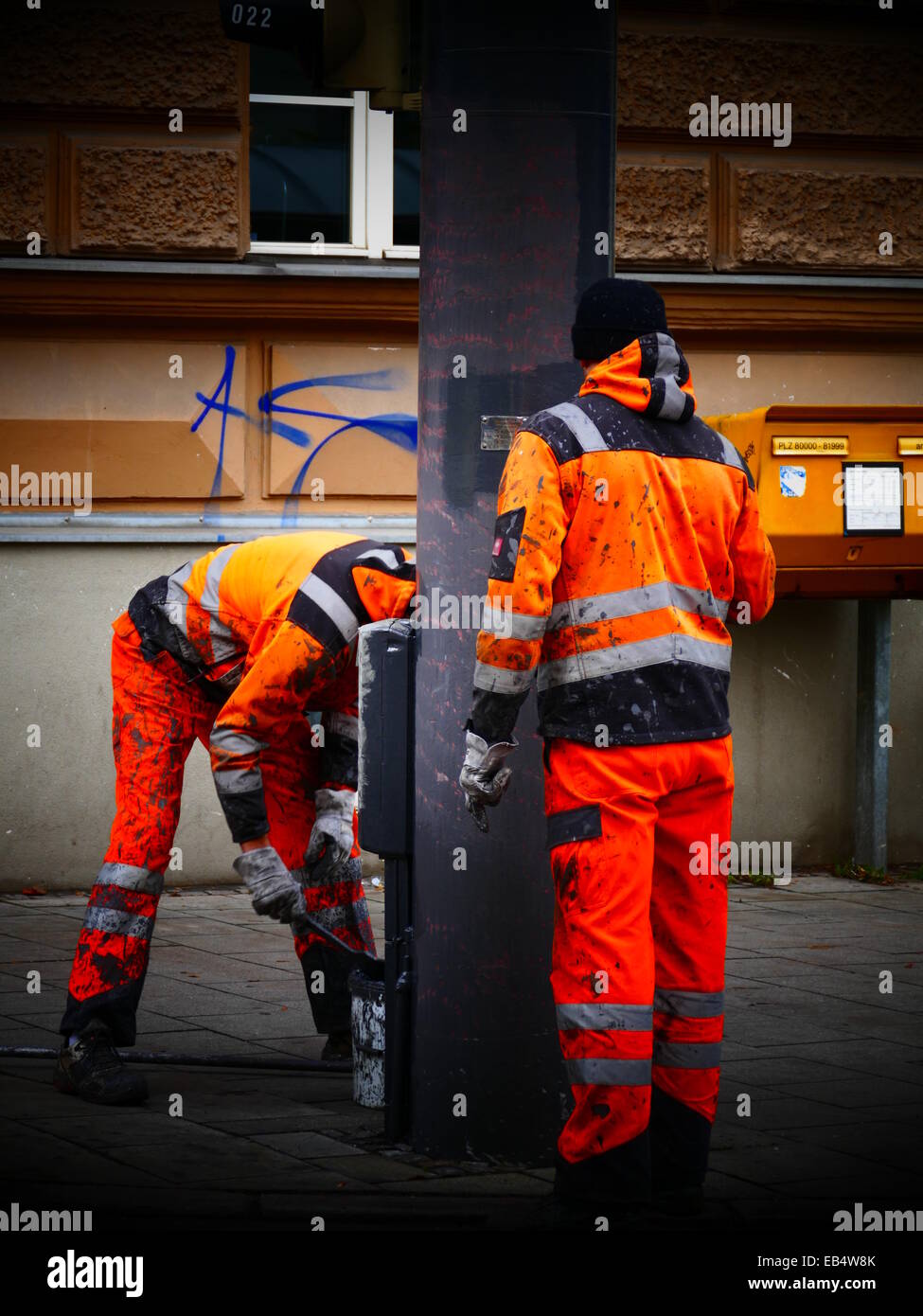 Gemeindearbeiter mit orange Workwear Warnweste Malerei Verkehr Pol Stockfoto