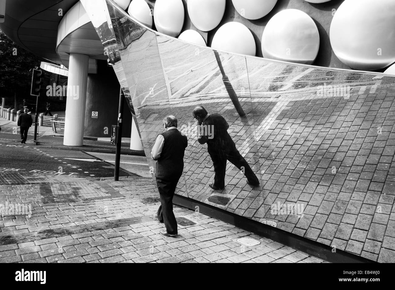 Schwarz / weiß-Bild von einem Mann zu Fuß in Birmingham und spiegelt sich in der Selfridges Gebäude, West Midlands, England, UK Stockfoto