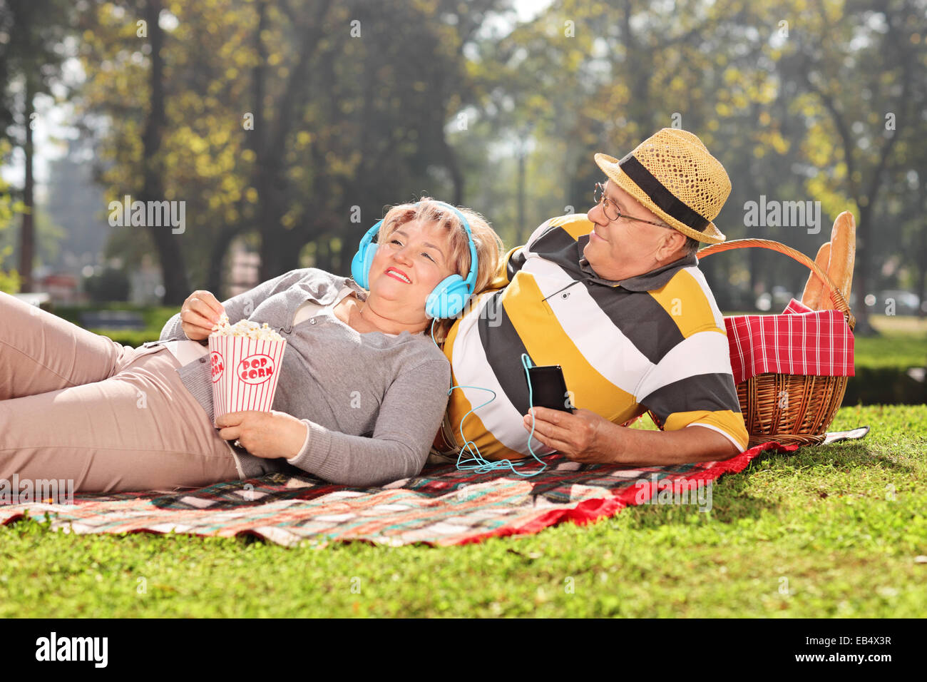 Älteres paar Musik hören über Kopfhörer im Park an einem sonnigen Tag Stockfoto