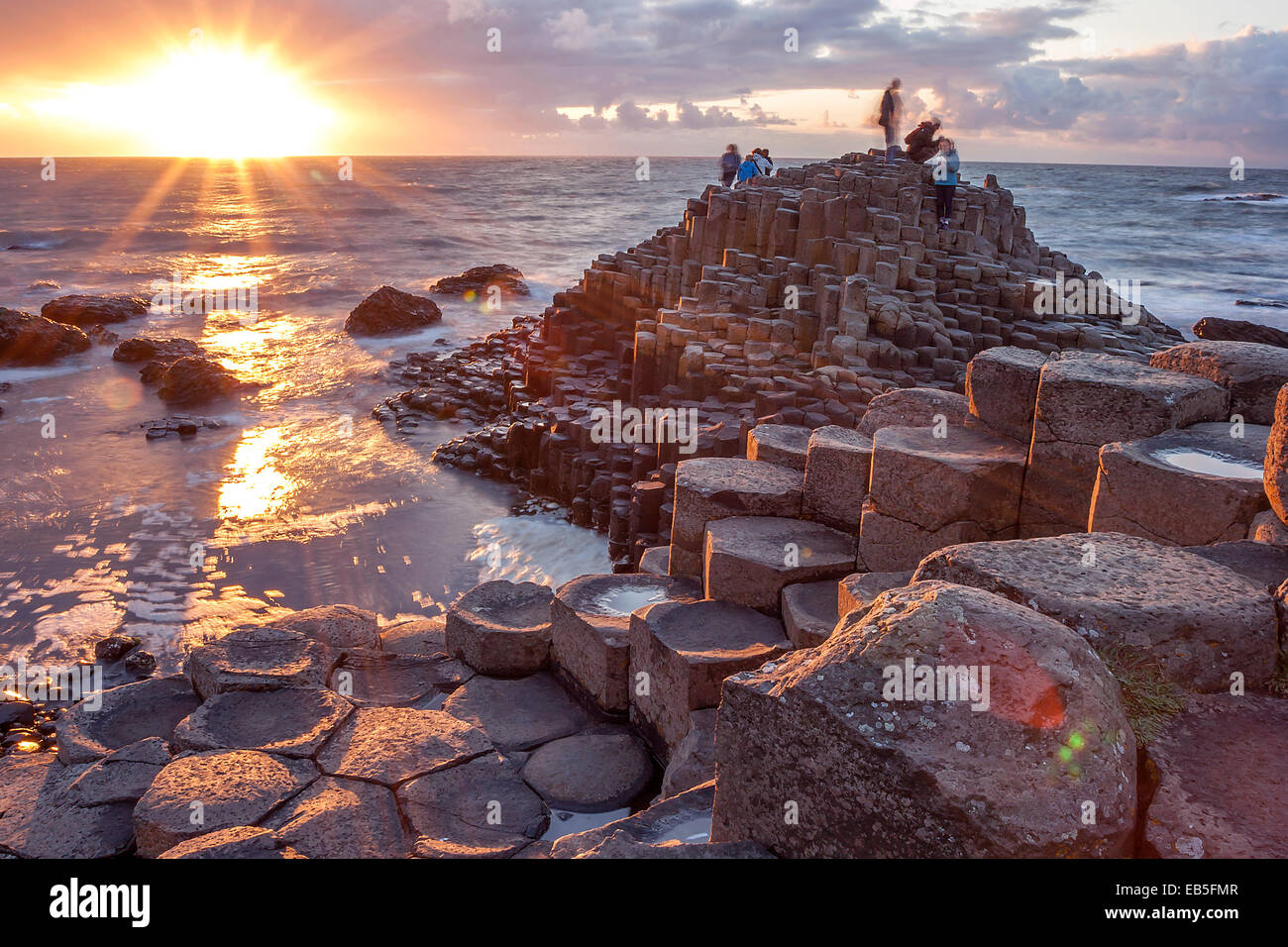 Besucher Giant s Causeway bei Sonnenuntergang in North Antrim, Nordirland Stockfoto