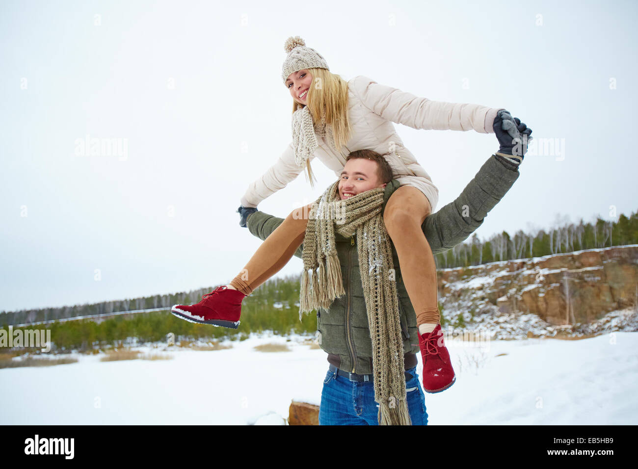 Junger Mann mit seiner Freundin auf Schultern in Winter park Stockfoto