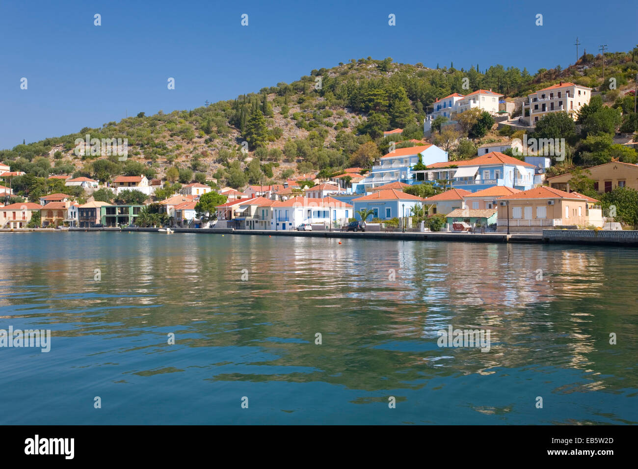 Vathy, Ithaka, Ionische Inseln, Griechenland. Farbenfrohe moderne Häuser mit Blick auf den geschützten Hafen. Stockfoto