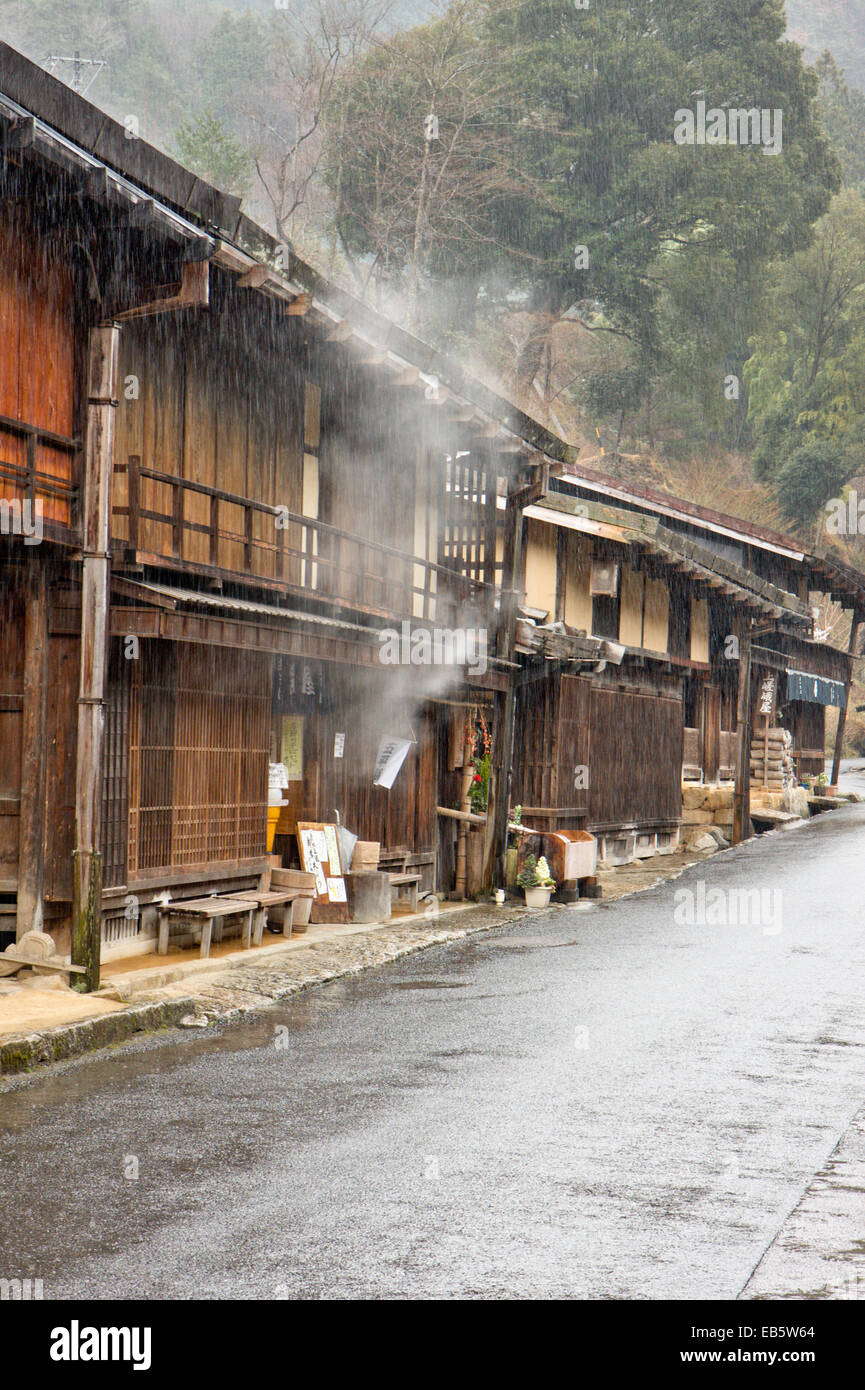 Blick auf die Terashita Straße in der Edo-Stadt Tsumago. Reihe von traditionellen Holzgebäuden, Geschäften und japanischen Gasthäusern, im strömenden Regen. Stockfoto