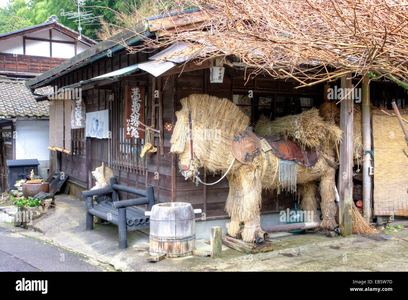 Tsumago, Japan. Straße von Terashita, an der Nakasendo Autobahn, traditionelle Edo-Periode Bauernhaus mit voller Größe Strohpferd Talisman draußen. Stockfoto