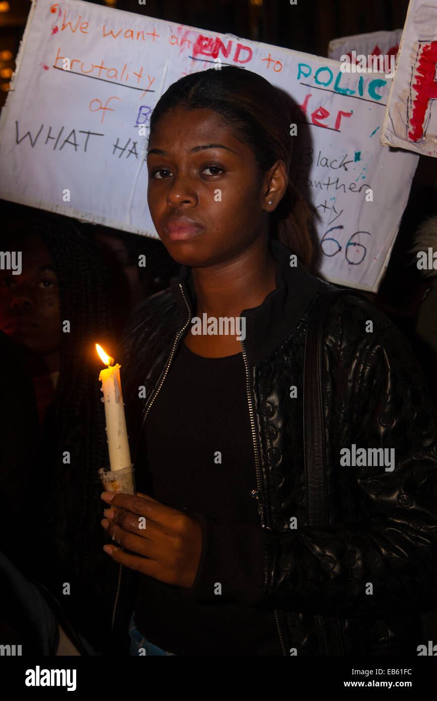 London, 26. November 2014. Eine Mahnwache für Teenager Mike Brown, der von einem Polizisten in Ferguson, Missouri in diesem Jahr erschossen wurde erfolgt außerhalb der US-Botschaft in London. Anti-Rassismus und Menschenrechte Aktivisten namens den "Notfall" Protest nach einem Gerichtsurteil, das Polizisten Darren Wilson des Mordes löscht. Bild: Eine düstere Frau hält eine Kerze, wie Hunderte Mike Brown in der amerikanischen Botschaft erinnern. Stockfoto