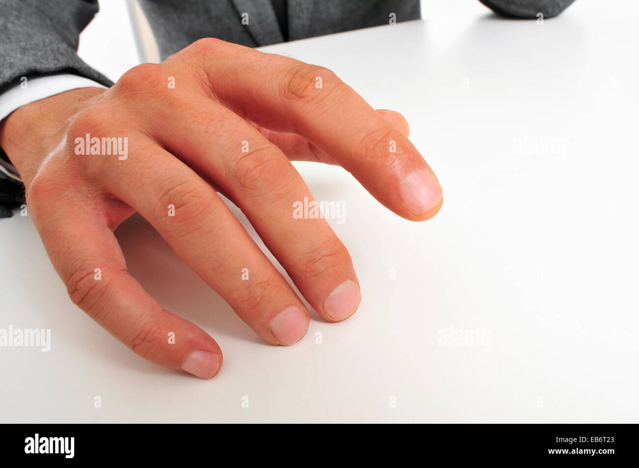 Mann trägt einen Anzug sitzen seine Finger auf den Tisch Trommeln Stockfoto